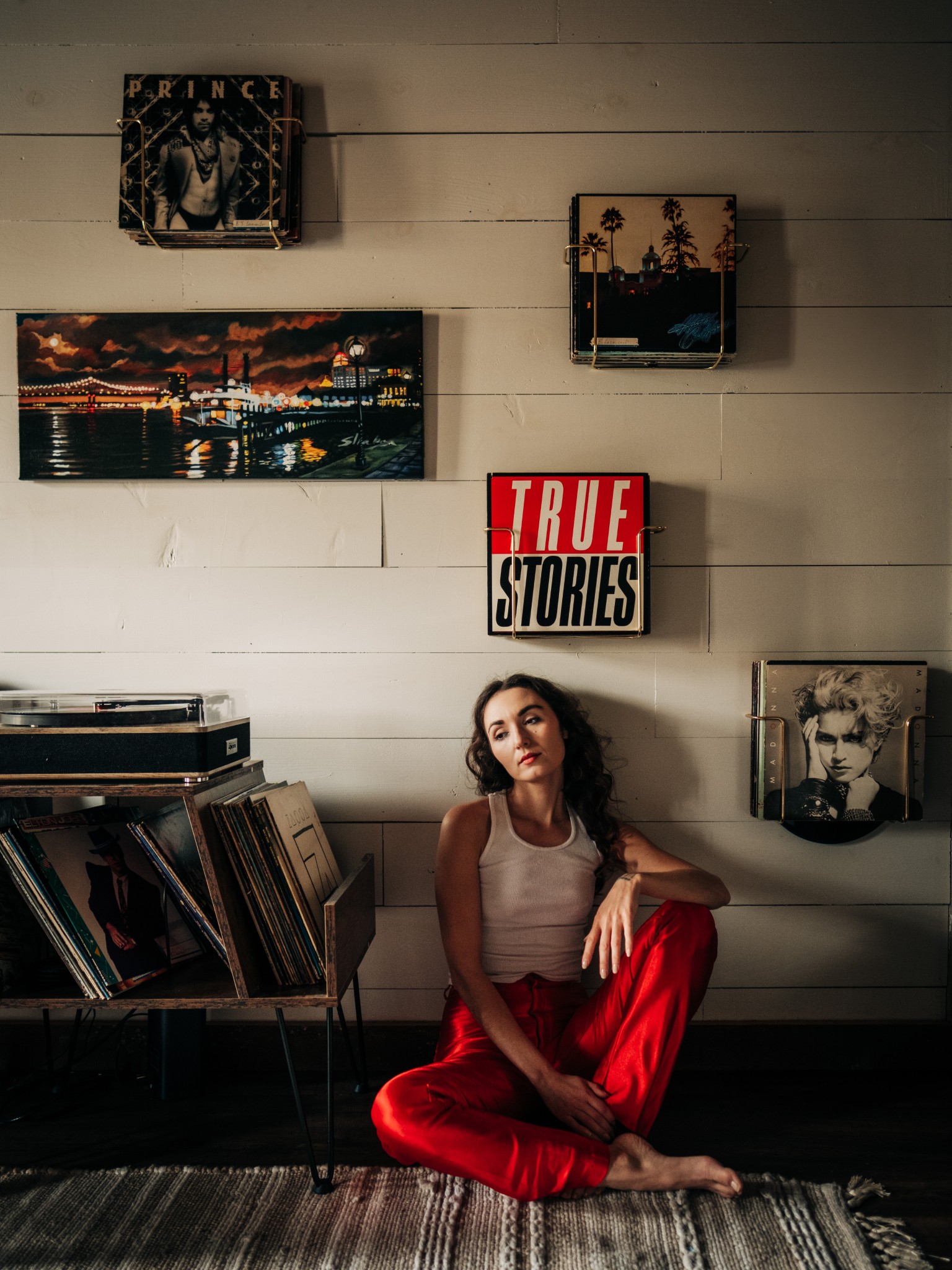 Portrait of a woman seated in a record room wearing red pants