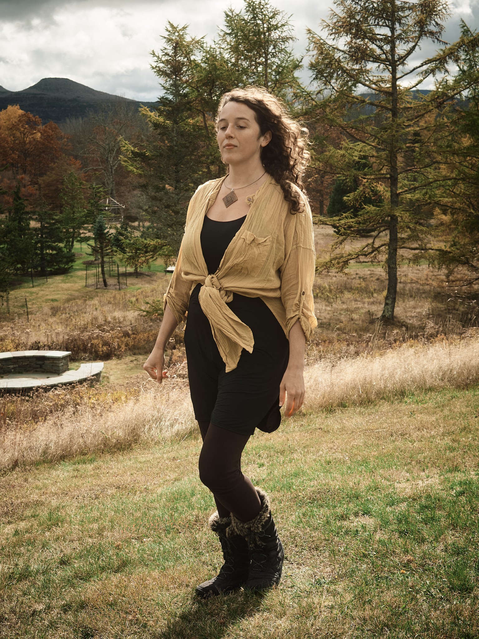 Woman walking through a mountain landscape in warm afternoon light.