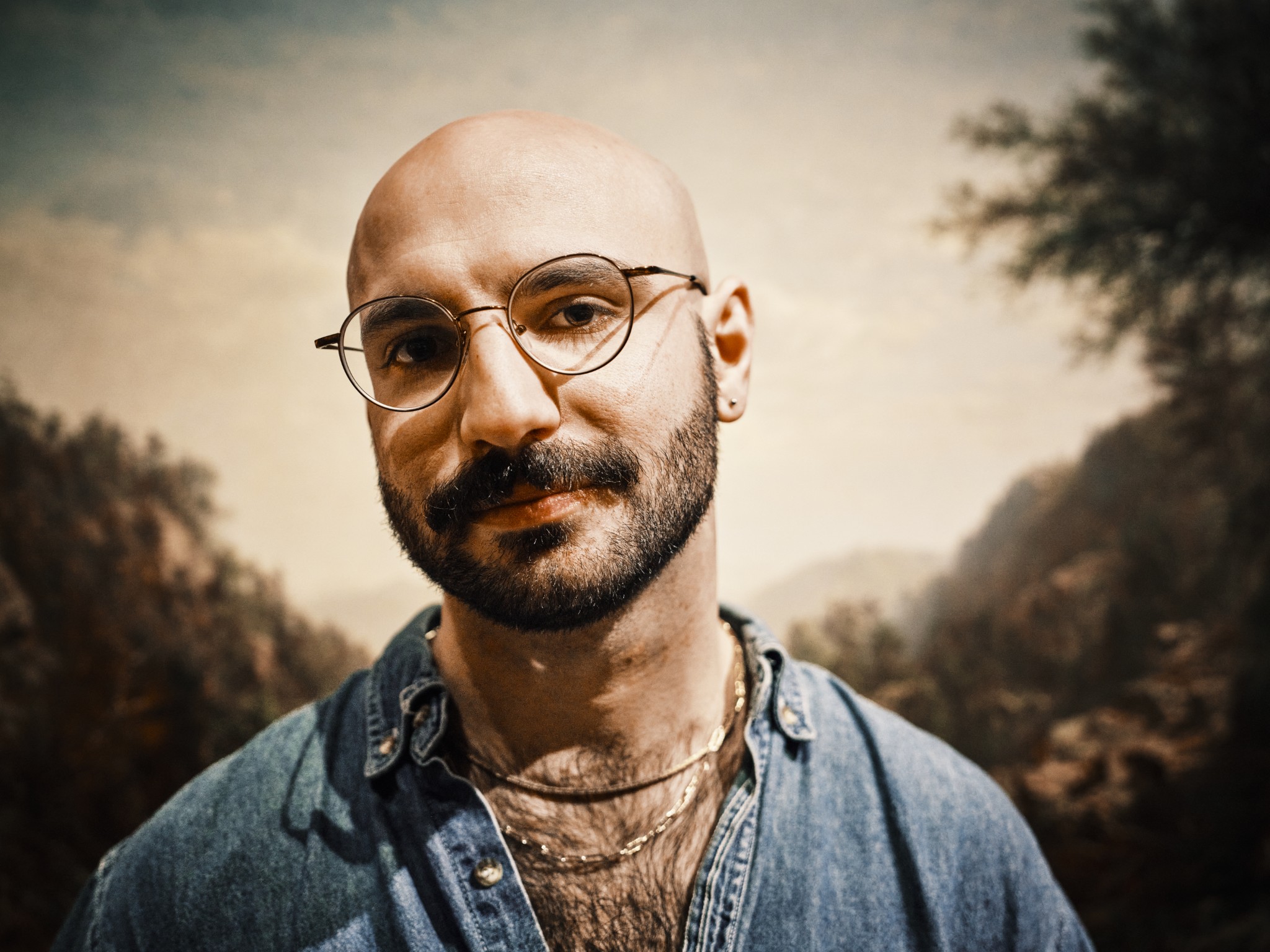 Close portrait of a man against a painted landscape.