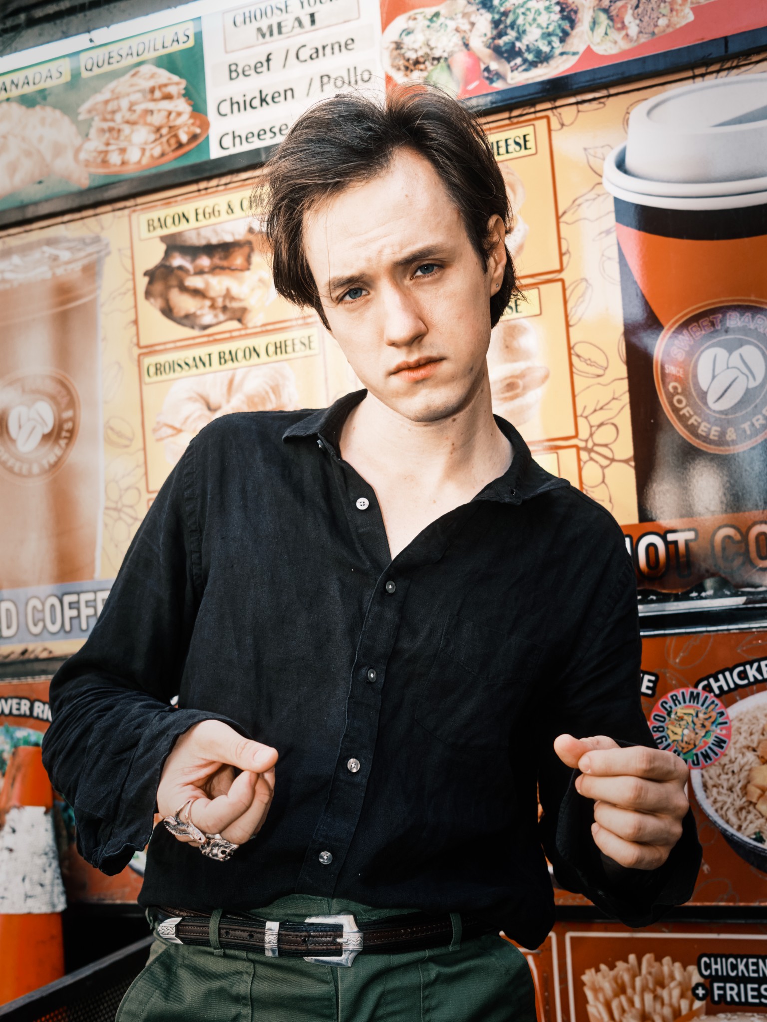 Expressive portrait of a man standing before a colorful food-truck menu.