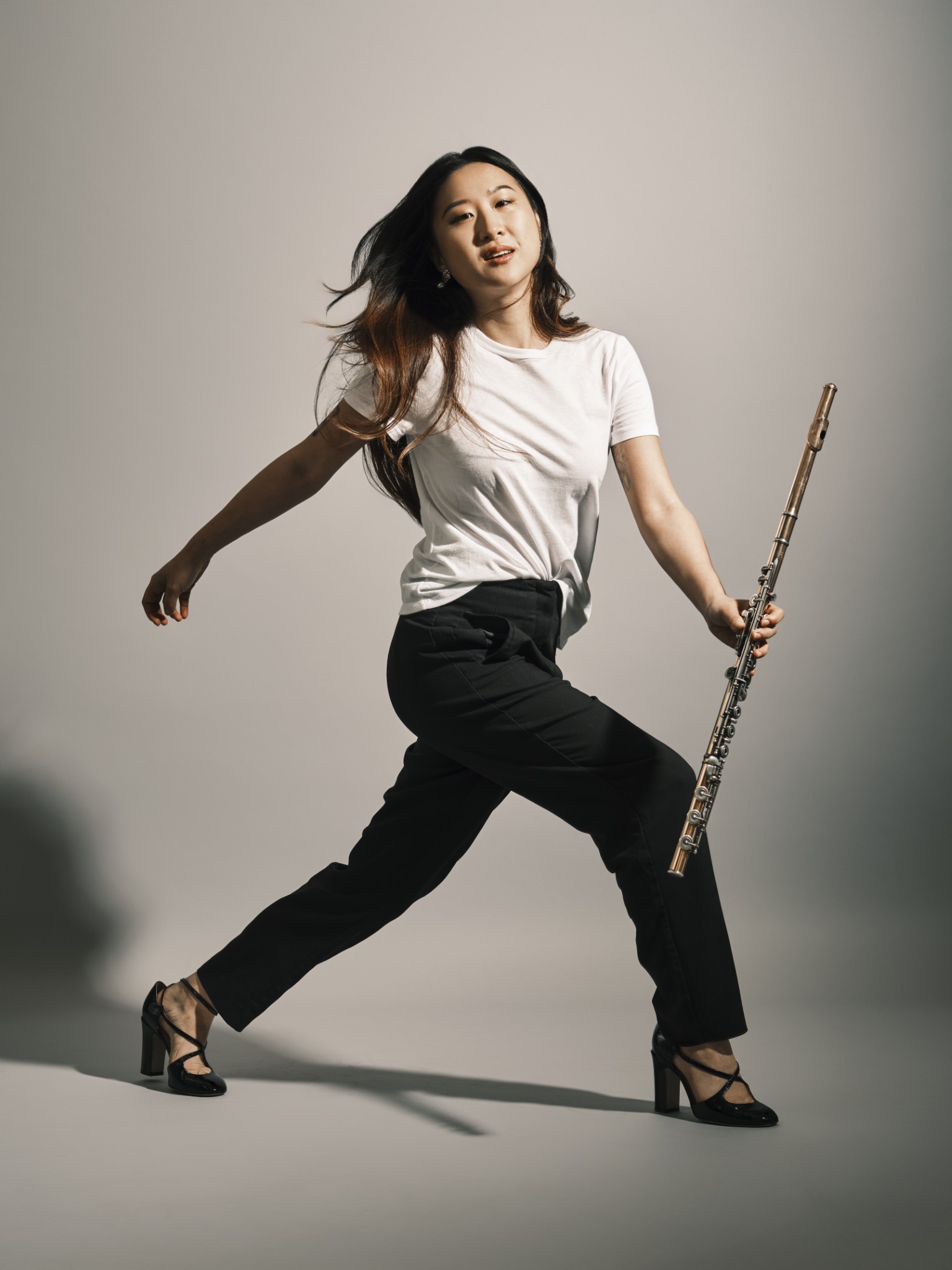 Musician moving dynamically through a studio while holding a flute.